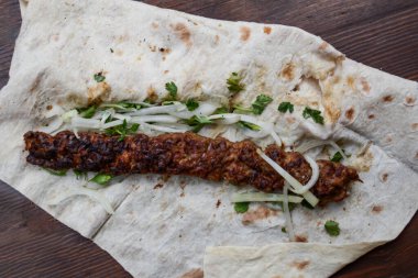 Pide, ekmek ve sebzeli bir tabakta shawarma.