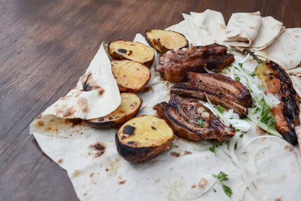 Kızarmış domuz kaburgası, ızgara patates ve beyaz tabak..