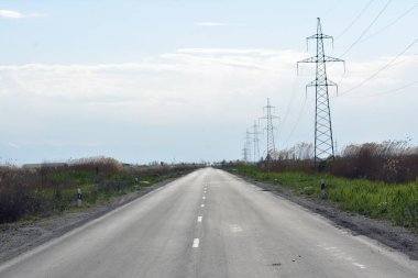 Dağlardaki yolda yüksek voltajlı elektrik hatları. Yol ve elektrik güçleri