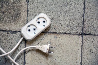 Arkaplanda elektrik prizi ve elektrik kablosu var..