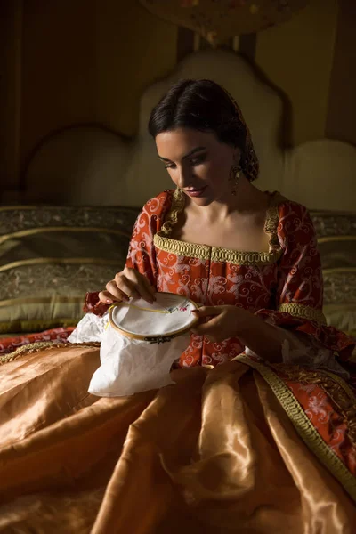 金色的中世纪卧房 有漂亮的天篷床 文艺复兴时期的一位女士在做刺绣服装 — 图库照片