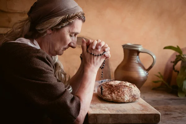穿着正宗农民复兴服装的女人在餐桌前祈祷 桌子上有面包 — 图库照片