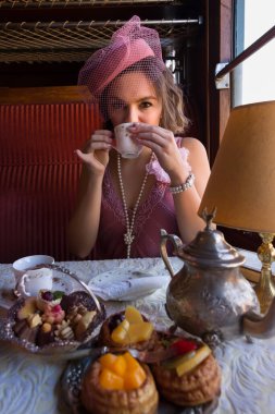 1920 'lerden kalma şık elbiseli bir bayanın otantik bir 1927 model buhar treninin kompartımanında çay içişini canlandırma sahnesi.