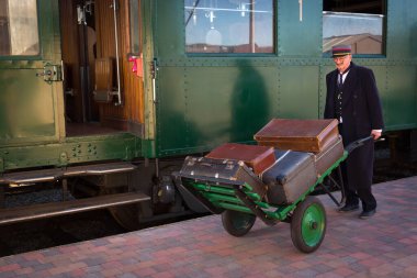 Vintage train baggage porter transporting luggage with an antique trolley