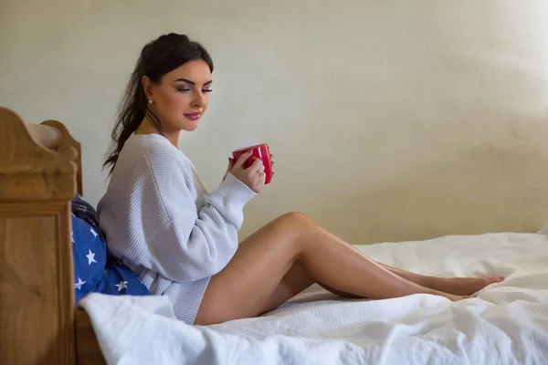 Attractive Young Woman Enjoying Mug Coffee Bed Wearing White Sweater — стоковое фото
