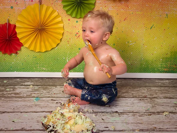 生日宴会上 一个金发碧眼的小男孩用木制勺子砸着生日蛋糕 在宴会上拍了许多精彩的照片 — 图库照片