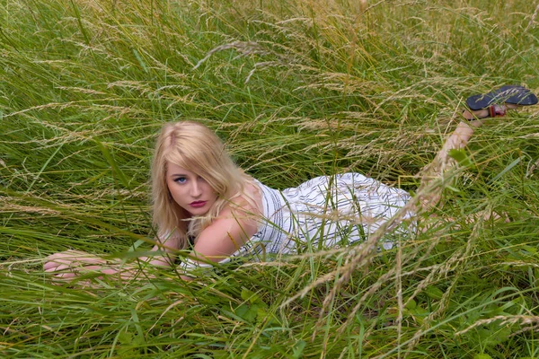 夢のような若いですブロンド女性リラックスしています下にある牧草地に高いです草 — ストック写真