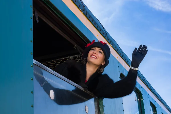 20世纪20年代的女人 身穿毛皮外套 头戴丁字帽 挂在一辆老式火车车厢的窗外 — 图库照片