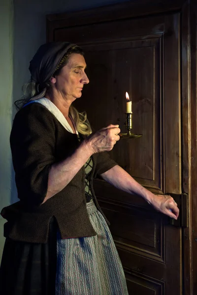 身着中世纪农民服装拿着燃烧的蜡烛的女士 — 图库照片