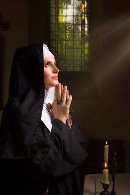 Genç yetişkin bir kadın, ortaçağ kilisesinde Katolik bir rahibenin peçesi ve otantik kıyafetleri içinde.
