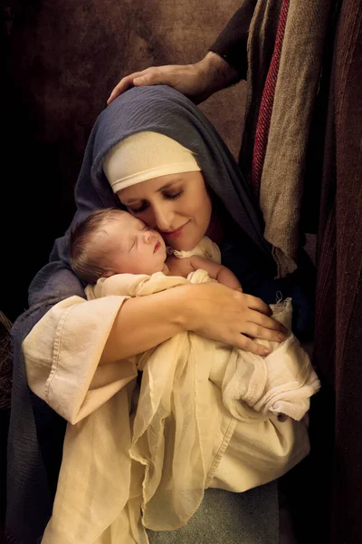 Mother playing Virgin Mary in a reenactment christmas nativity scene with her own 8 days old baby