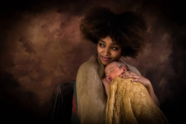 茶色の背景に茶色のスカーフを着用した新生児を持つ美しいアフリカのエチオピアの母親 ストック画像
