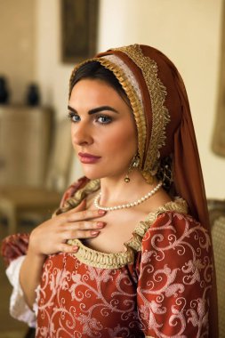 Otantik Rönesans elbisesi giymiş bir kadının yakın plan portresi ve aynı Fransız başlığı..