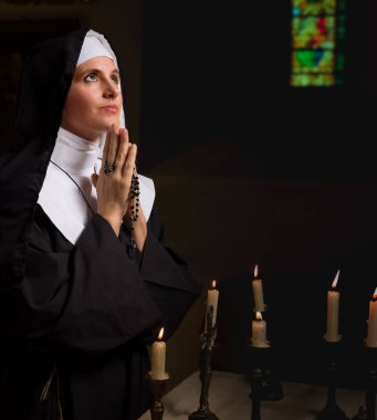 Genç yetişkin bir kadın, ortaçağ kilisesinde Katolik bir rahibenin peçesi ve otantik kıyafetleri içinde.