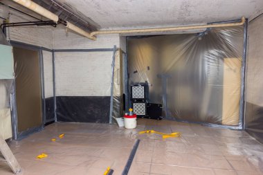 Asbest temizleme işlemi bodrumda devam eden ısıtma borularına yapılan hakaretle çalışır. Tüm duvarlar plastikle kaplıdır ve filtrelenmiş hava çıkarımı çok liflidir.