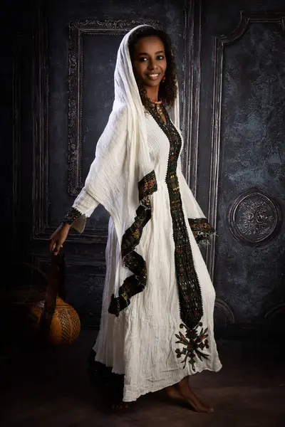 エチオピアの若い女性は彼女の伝統的な民族衣装を着て 中空のグルメで作られたハンドバッグを運ぶ ストック画像