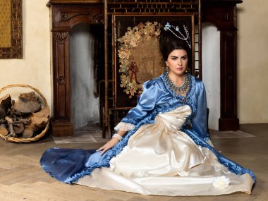 Rokoko kraliçesi Marie Antoinette tarzı giyinmiş ve Fransız şatosunun iç kısımlarında otantik bir peruk takmış güzel bir kadın.