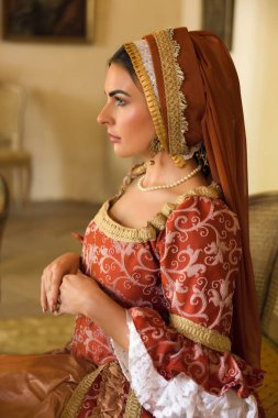 Otantik Rönesans elbisesi giymiş bir kadının yakın plan portresi ve aynı Fransız başlığı..