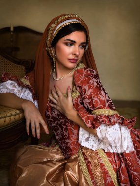 Young woman in medieval renaissance costume and French hood sitting on the floor holding a letter