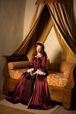 Bir Rönesans Kraliçesi 'nin canlandırma sahneleri. Tudor tarzında. Bir Fransız şatosunda antik bir yatak üzerinde poz veriyor.