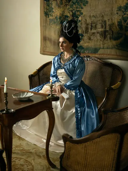 Rokoko kraliçesi Marie Antoinette tarzı giyinmiş ve Fransız şatosunun iç kısımlarında otantik bir peruk takmış güzel bir kadın.