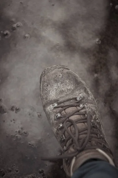 Vertical shot of hiking boot stepping into mud