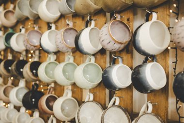 Ahşap duvarda asılı renkli seramik kupalar koleksiyonu