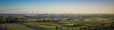 Aerial panorama view on Waasland rural area mixed with wind turbines and harbor of Antwerp in the far distance during sunrise clipart