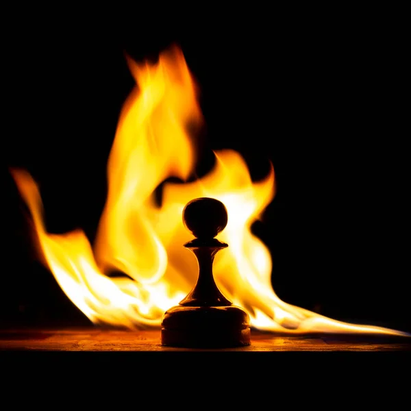 stock image chess board on fire with figures in the dark, front and background blurred with bokeh effect