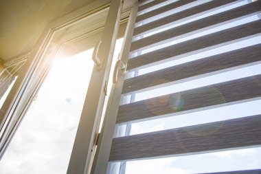 Havalandırmaya açılan plastik bir pencere. Mavi gökyüzüne karşı körlük ve sivrisinek ağı.