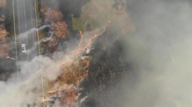 İlkbaharın başlarında, otobanın yakınında yanan temellerin üzerinde kuru çimen yangını