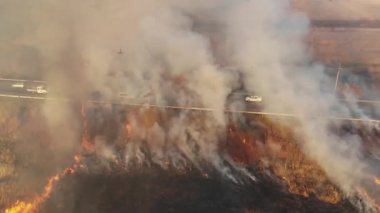 İlkbaharın başlarında, otobanın yakınında yanan temellerin üzerinde kuru çimen yangını