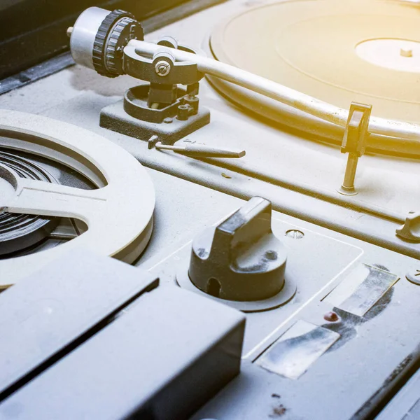 an old reel-to-reel tape recorder and gramophone in a thick layer of dust, the front and back background blurred with a bokeh effect