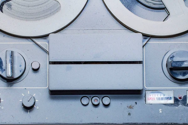 an old reel-to-reel tape recorder and gramophone in a thick layer of dust, the front and back background blurred with a bokeh effect