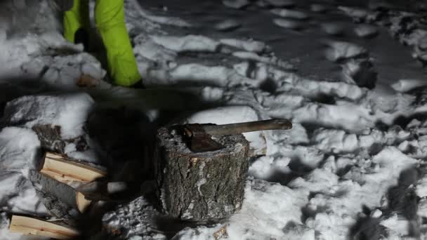 夜に雪の中で木を切り刻む男が家を暖めるために — ストック動画