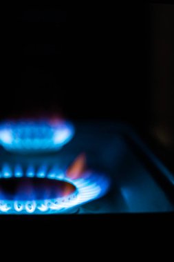 Siyah arka planda yanan bir gaz ocağı üzerine yüz dolarlık banknot, ön ve arka planda bokeh etkisi ile bulanıklaştırılmış.