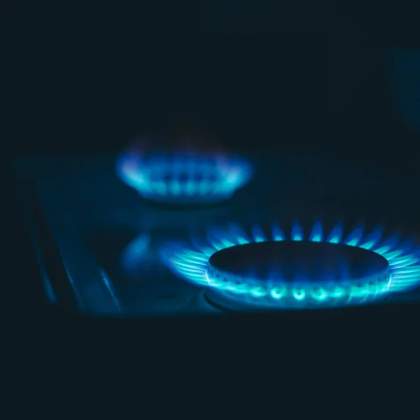 a hundred dollar bill on a gas burner with a burning fire on a black background, the front and back background is blurred with a bokeh effect