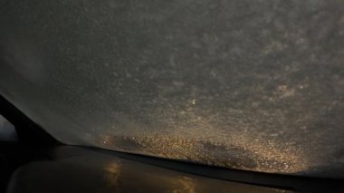 Geceleri arabanın ön camında kar eritme işlemi. Erimiş kar ve buz yavaş yavaş aşağı kayıyor. İçeriden. ısıtılmış cam.