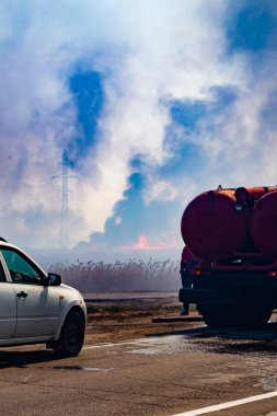 İtfaiyeciler ilkbaharda yangını söndürür. Tehlikeli bir nesnenin yanında ölü bir odun. Ön ve arka plan bokeh etkisi ile bulanıklaşır.