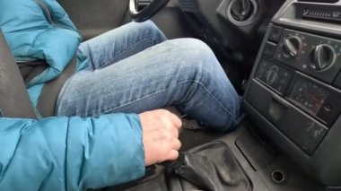Bir adam, engebeli bir yolda sallanan bir arabada, çok kötü bir yolda eski bir arabanın vitesini değiştiriyor.
