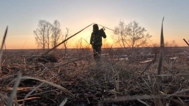 Hazine avcısı, baharın erken saatlerinde, gün batımında, doğada güzel bir ortamda, kuru otların arasında hazine arıyor.
