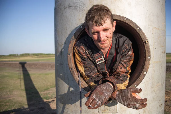 stock image a working industrial climber taking a smoke break from painting a water tower. difficult work in a closed space