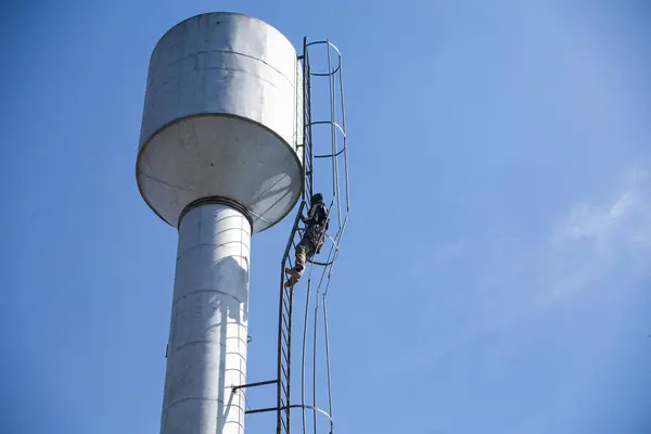 an industrial climber repairing a water tower using special equipment to prevent drought