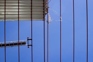 Mavi gökyüzünün arka planına karşı vinç ve yükleyiciler kullanarak hangar metal yapılarının kurulumu