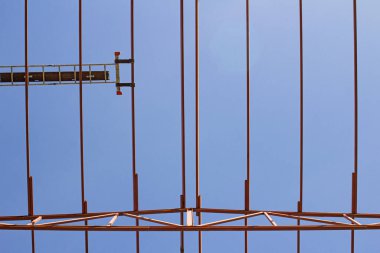 Mavi gökyüzünün arka planına karşı vinç ve yükleyiciler kullanarak hangar metal yapılarının kurulumu