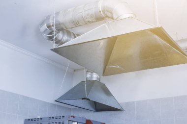 Mutfaktaki havalandırma şemsiyesi yemek hazırlama alanında ve masa başında.
