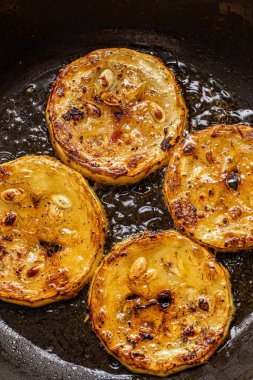 Fırınlanmış tavada zeytinyağında baharatlı kabak kızartma işlemi.