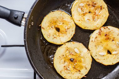 Fırınlanmış tavada zeytinyağında baharatlı kabak kızartma işlemi.