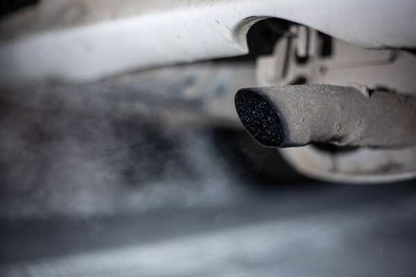 exhaust pipe of a car with exhaust gases on a winter night in the dark