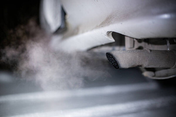 exhaust pipe of a car with exhaust gases on a winter night in the dark